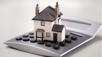 Photograph of a model house on top of a calculator.